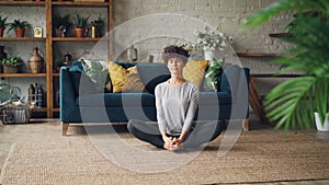 Slender young woman is bending forward to one leg then relaxing in cobbler`s pose during yoga practice at home. wellness