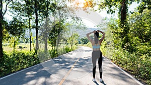 A slender young woman in a sportswear jogging down the street in the bright morning. girl running in the autumn forest rear view.