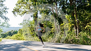 A slender young woman in a sportswear jogging down the street in the bright morning. girl running in the autumn forest rear view.