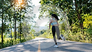 A slender young woman in a sportswear jogging down the street in the bright morning. girl running in the autumn forest rear view.