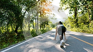 A slender young woman in a sportswear jogging down the street in the bright morning. girl running in the autumn forest rear view.