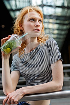 Slender young woman in striped shirt drinking refreshing mojito