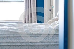 A slept-in bed with a messy sheet, no blankets, in a blue and white bedroom home design