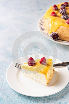 Slice of angel food cake with lemon curd and frozen berries raspberry and blackberry.