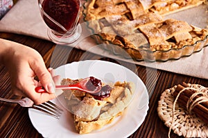 Slice of Apple Pie on colorful plate with fork and jam. Close up view