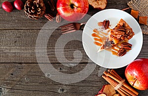 Slice of autumn caramel apple pecan cheesecake, top view corner border over wood