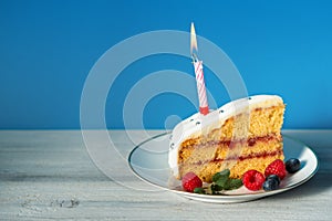 Slice of birthday cake with candle and berries