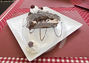 Slice of black forest cake on a white plate on a table