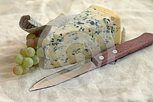 Slice of blue cheese with knife and grapes