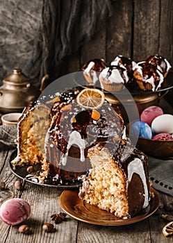 Slice of bread kulich and Easter cake with chocolate and nuts on rustic wooden table with colored easter eggs. Happy Easter