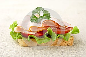 Slice of bread with lettuce,cold cuts on linen tablecloth