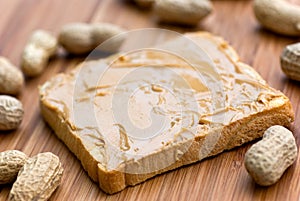 Slice of bread with peanut butter spread on wooden
