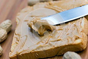 Slice of bread with peanut butter spread on wooden