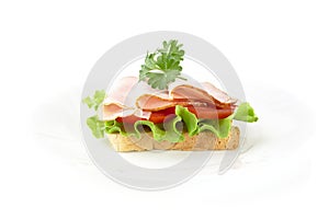 Slice of bread on plate with lettuce,cold cuts on white