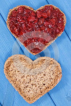 Slice of bread with strawberry jam for breakfast. Shape of heart
