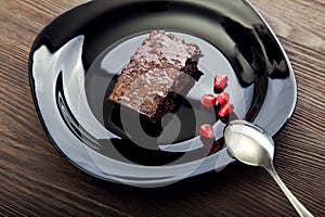 Slice of brownie on black plate on a wooden table