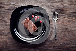 Slice of brownie on black plate on a wooden table