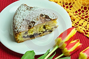 A slice of cake with jam and red and yellow tulips