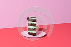 Slice of cake minimalist on a red background. Chocolate and mint layered cake