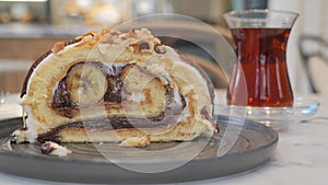 A slice of cake on serveware next to a glass of tea drinkware