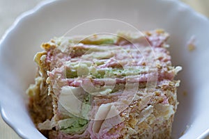 A slice of cake in a white plate. Colored cream for a puff cake. Homemade baking. children`s birthday.