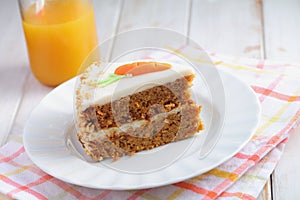 Slice of carrot cake  Pastel de zanahoria with icing and marzipan carrot on white background with carrot juice