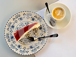 Slice of cheesecake with strawberry jelly served with espresso