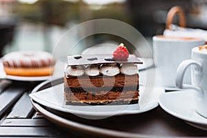 Slice of chocolate cake, Cutlery steak basket and donot with coffee on the table