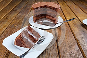 Slice of chocolate cake with filling and semisweet chocolate ganache frosting. Next to the sliced cake_side view