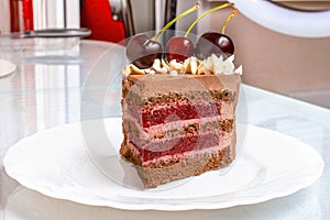 Slice Chocolate caramel cake with cherries on white plate