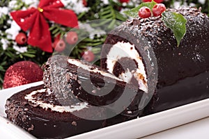 Slice of Christmas yule log cake on plate with decoration