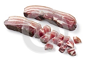 Slice and cubes of Italian pancetta on white background close up