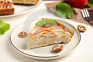 Slice of delicious apple pie on white wooden table