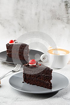 A slice of delicious chocolate cake with cherry on top on marble background. Piece of Cake on a Plate. Sweet food. Sweet dessert.