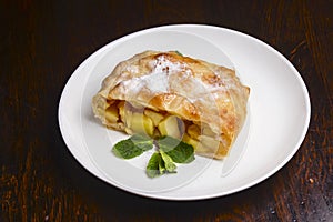 Slice of delicious fresh baked Rustic Apple Pie served on a white plate on wooden table background