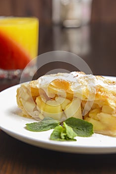 Slice of delicious fresh baked Rustic Apple Pie served on a white plate on wooden table background