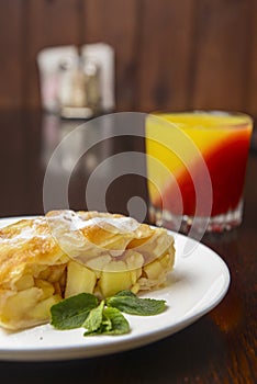 Slice of delicious fresh baked Rustic Apple Pie served on a white plate on wooden table background