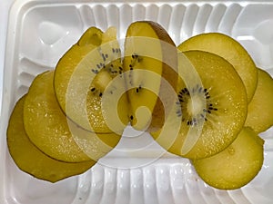 The slice delicious of golden kiwi fruit is occurring on the white tray enriched vitamin and nutrition