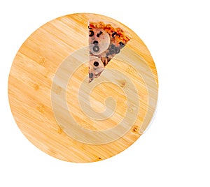A slice of delicious pizza with ham, mozzarella, mushrooms and olives on a wooden round platter, isolated on white background
