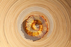 Slice of dried pineapple on a round wooden plate. Healthy natural sweets. Top view, copy space