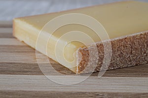 Slice of french comte cheese on wood cutting board