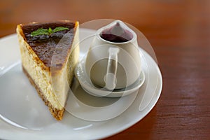 Slice of gourmet fresh cake pie with a jar of blueberry on a white plate with wooden table.