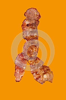 A slice of grilled bacon isolated on a yellow background. Clipping path. Full depth of field