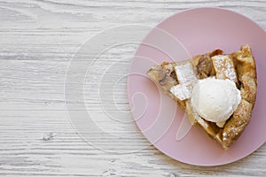 Slice of homemade apple pie with ice cream on pink plate. White wooden background. Copy space. Flat lay, overhead, from above