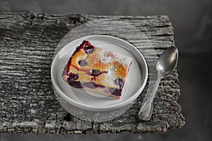 A slice of homemade clafoutis cherry pie - traditional french dessert in a gray plate