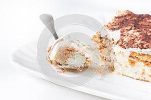 Slice of homemade tiramisu on a plate, on white background, side view