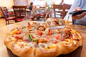 Slice hot pizza deluxe with melting cheese in woman hand.