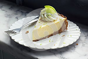 Slice of Key Lime Pie with Whipped Cream and Lime Zest on a Plate