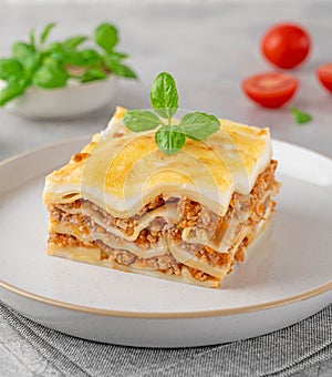 Slice of Lasagna bolognese with meat sauce and bechamel with melted cheese on top and fresh basil. Italian cusine. Copy space