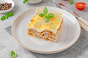 Slice of Lasagna bolognese with meat sauce and bechamel with melted cheese on top and fresh basil. Italian cusine. Copy space